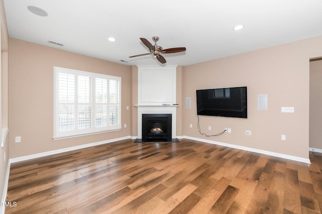 unfurnished living room featuring recessed lighting, a fireplace with flush hearth, wood finished floors, visible vents, and baseboards