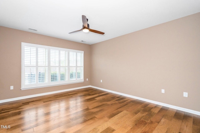 spare room with visible vents, ceiling fan, baseboards, and wood finished floors