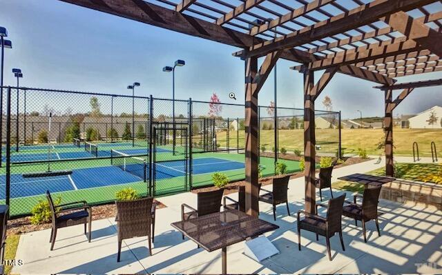 view of tennis court with fence and a pergola