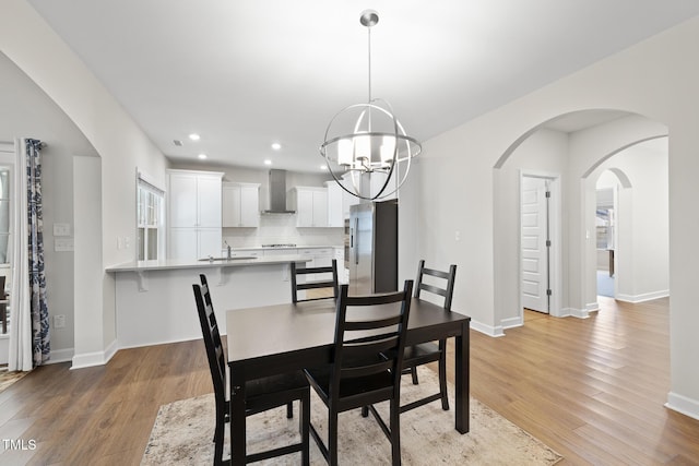 dining room with an inviting chandelier, sink, and light wood-type flooring