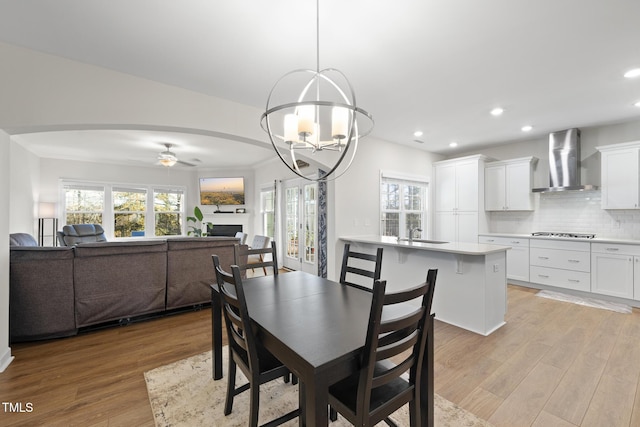 dining area with ceiling fan with notable chandelier, ornamental molding, sink, and light hardwood / wood-style floors