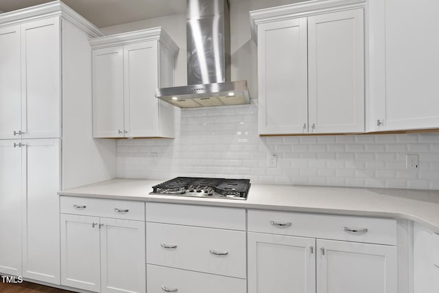 kitchen with wall chimney range hood, light stone counters, tasteful backsplash, stainless steel gas cooktop, and white cabinets