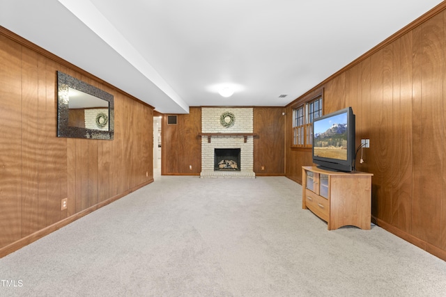 unfurnished living room with a brick fireplace, light colored carpet, and wooden walls