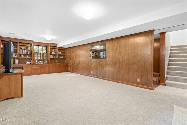 unfurnished living room with light colored carpet and wood walls