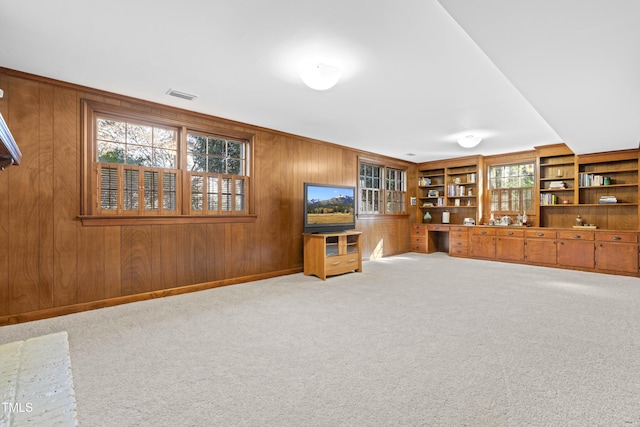 unfurnished living room featuring light carpet and wood walls