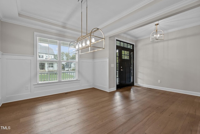 unfurnished dining area featuring hardwood / wood-style flooring, ornamental molding, and a chandelier