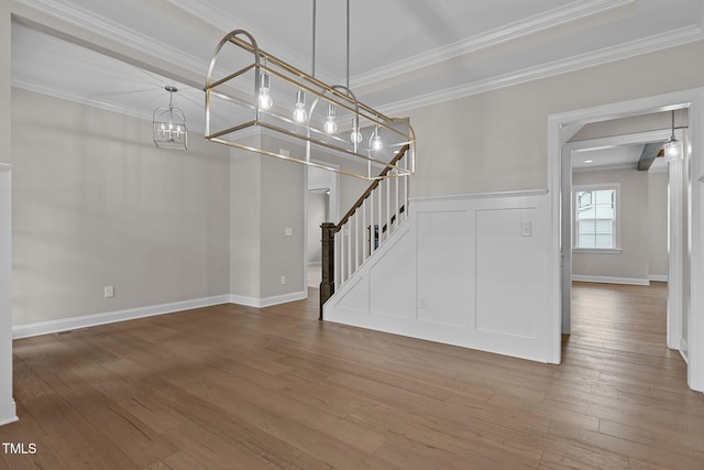 unfurnished living room with hardwood / wood-style flooring, ornamental molding, and an inviting chandelier