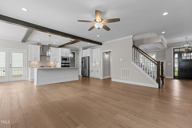 unfurnished living room featuring ornamental molding, ceiling fan with notable chandelier, beam ceiling, and light hardwood / wood-style floors