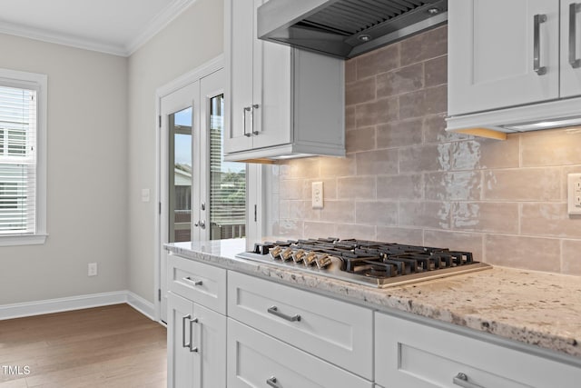 kitchen featuring crown molding, stainless steel gas stovetop, custom exhaust hood, and white cabinets