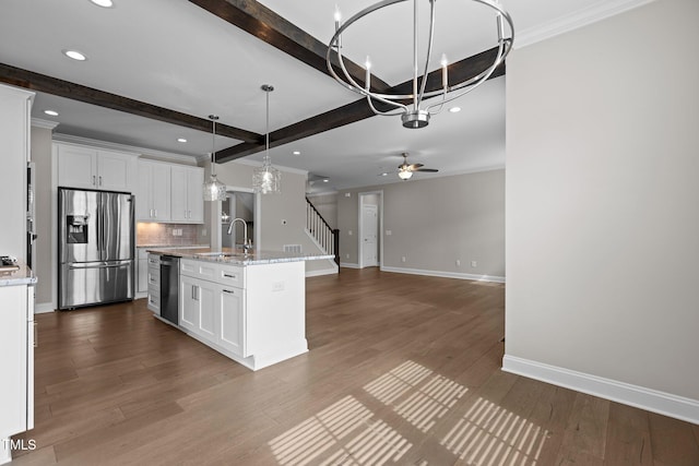 kitchen featuring white cabinetry, appliances with stainless steel finishes, decorative light fixtures, and a center island with sink