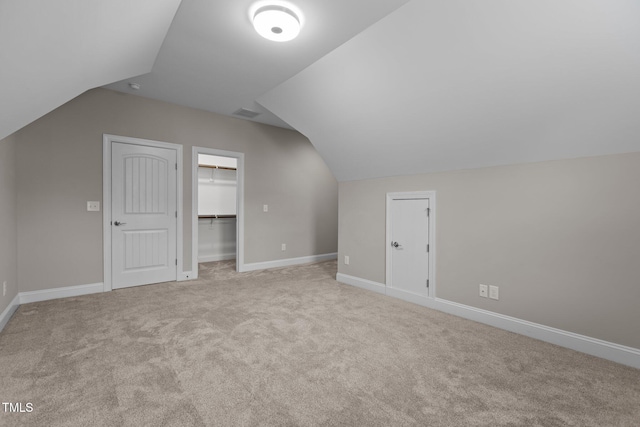 bonus room with lofted ceiling and light colored carpet