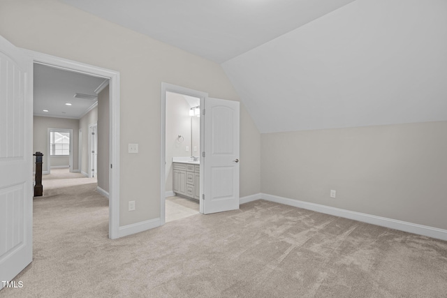 unfurnished bedroom with lofted ceiling, ensuite bath, and light carpet