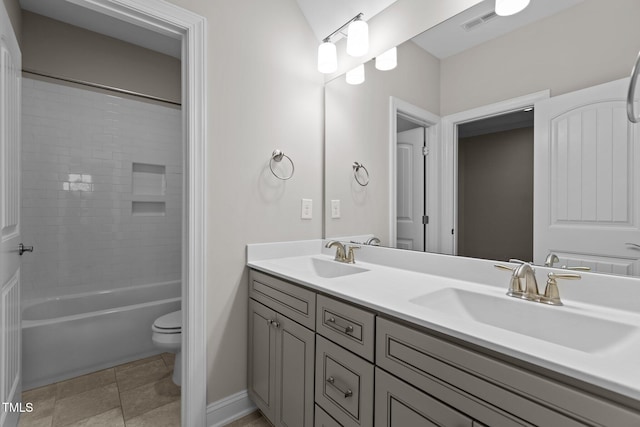 full bathroom with tile patterned flooring, vanity, tiled shower / bath combo, and toilet