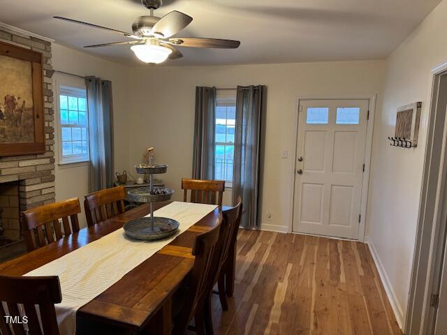 dining space with a wealth of natural light, a fireplace, light hardwood / wood-style floors, and ceiling fan