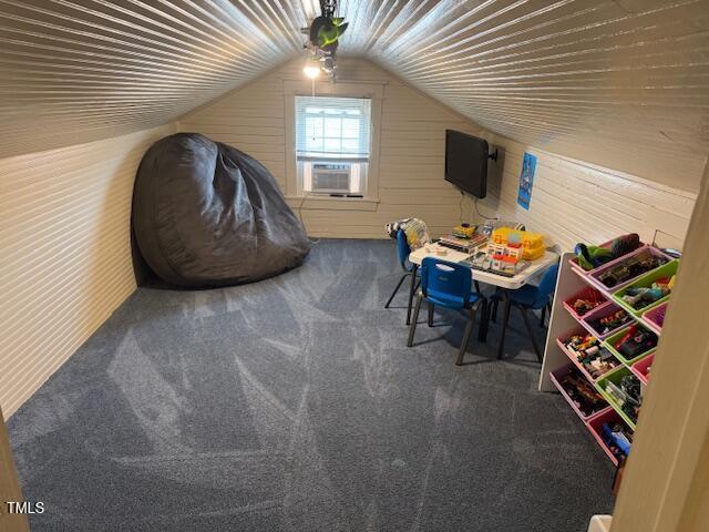 interior space with cooling unit, vaulted ceiling, wood walls, and carpet