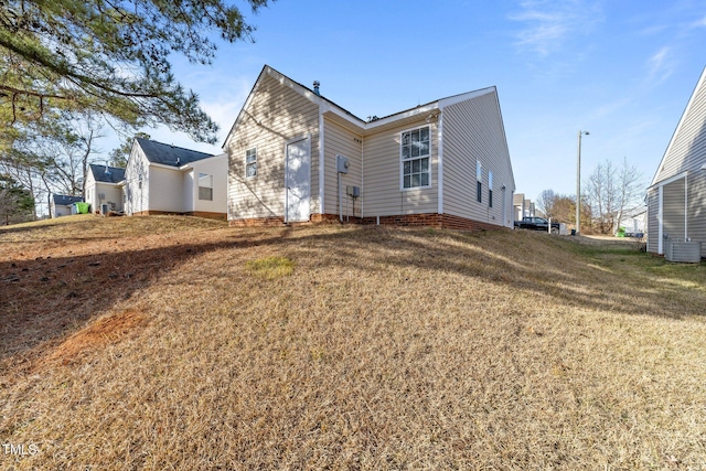 rear view of property with a lawn and central air condition unit