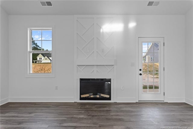 531 Southerland Peak, Raeford, NC 28376 - unfurnished living room featuring a glass covered fireplace, visible vents, and dark wood-style floors