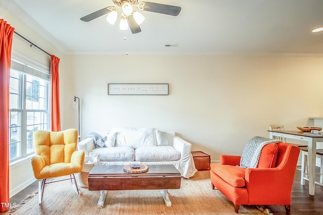 living room featuring wood-type flooring, ornamental molding, and ceiling fan