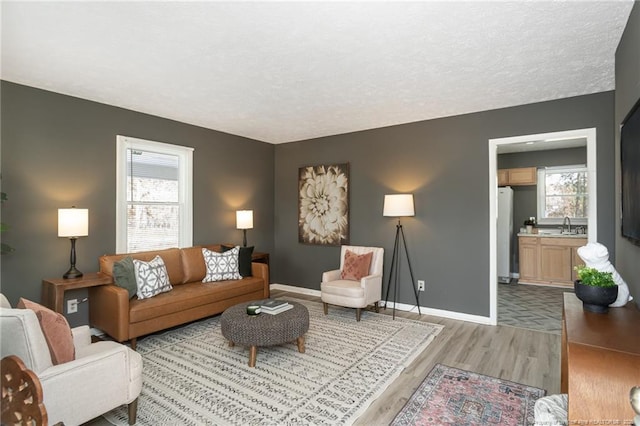 living room with sink, a textured ceiling, and light wood-type flooring