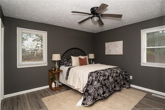 bedroom featuring dark hardwood / wood-style flooring, a textured ceiling, and ceiling fan