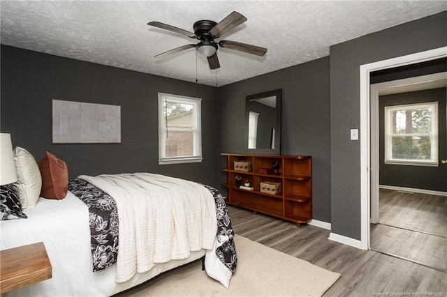 bedroom with multiple windows, a textured ceiling, ceiling fan, and hardwood / wood-style flooring