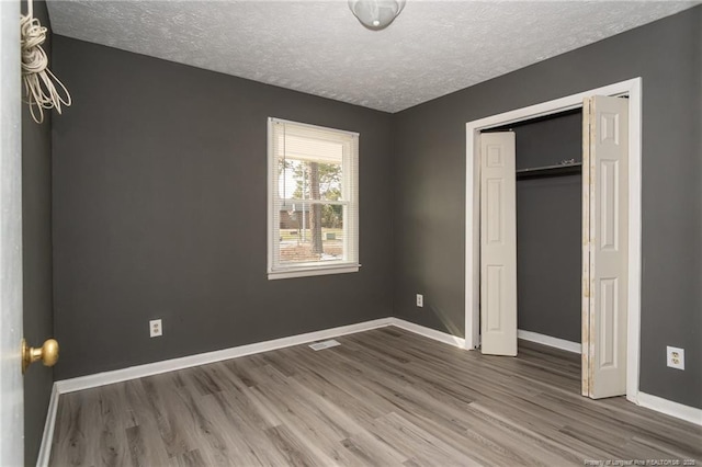 unfurnished bedroom featuring a closet, wood-type flooring, and a textured ceiling