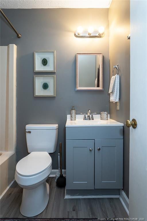 full bathroom with vanity, hardwood / wood-style flooring, tub / shower combination, and toilet