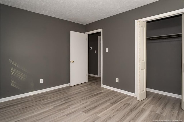 unfurnished bedroom with a closet, light hardwood / wood-style floors, and a textured ceiling