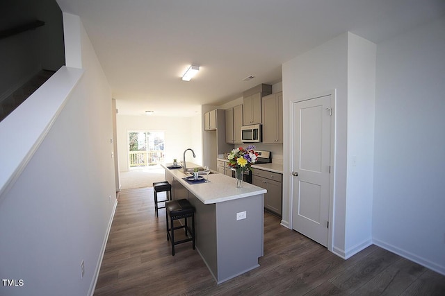 kitchen with sink, gray cabinetry, a center island with sink, appliances with stainless steel finishes, and dark hardwood / wood-style floors