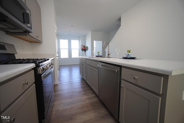 kitchen with sink, dark wood-type flooring, gray cabinets, and stainless steel appliances