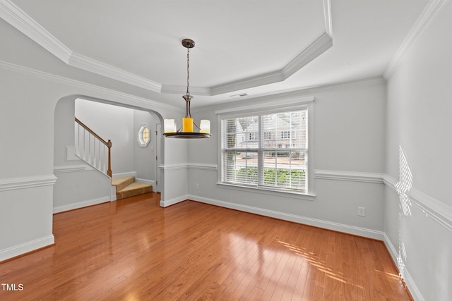 unfurnished dining area featuring crown molding, hardwood / wood-style floors, and a tray ceiling