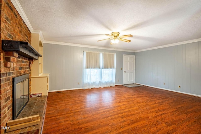 unfurnished living room featuring crown molding, hardwood / wood-style flooring, ceiling fan, a fireplace, and a textured ceiling