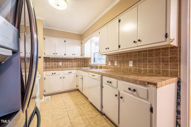 kitchen with tile countertops, refrigerator, white cabinetry, decorative backsplash, and white dishwasher