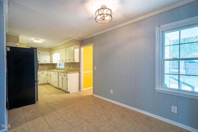 kitchen featuring crown molding, stainless steel refrigerator, dishwasher, a wealth of natural light, and white cabinets