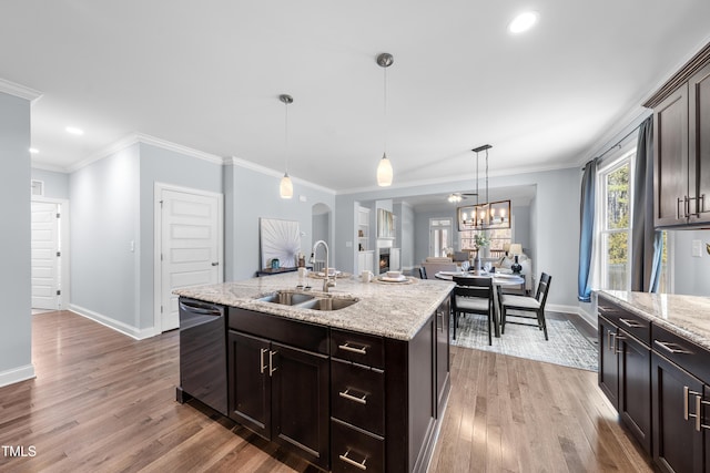 kitchen with dark brown cabinetry, dishwasher, wood finished floors, a kitchen island with sink, and a sink