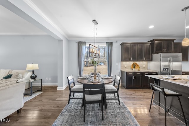 dining space with an inviting chandelier, baseboards, ornamental molding, and dark wood-type flooring