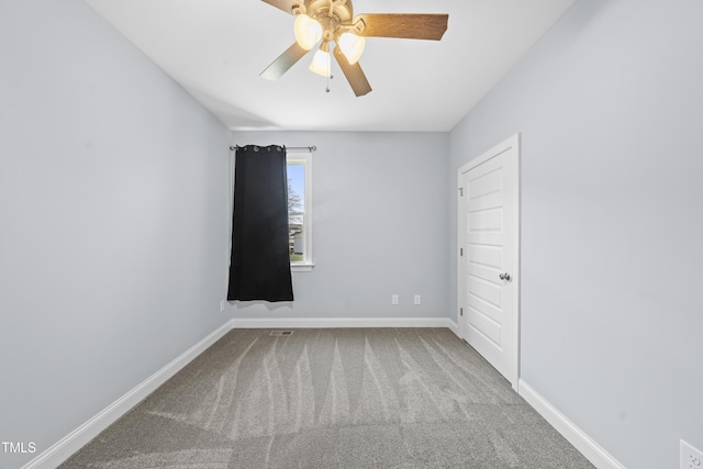 carpeted spare room featuring a ceiling fan and baseboards