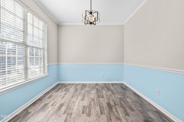 spare room with crown molding, baseboards, wood finished floors, and a healthy amount of sunlight