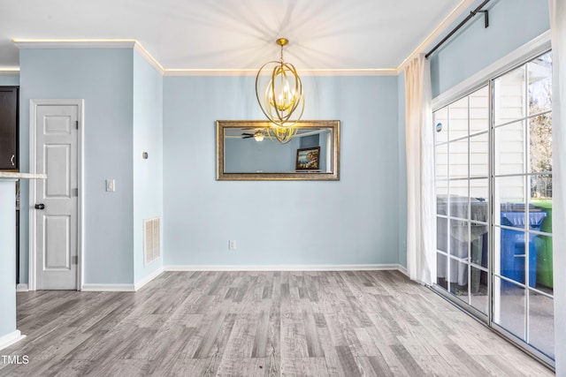 spare room featuring visible vents, ornamental molding, a chandelier, light wood-type flooring, and baseboards