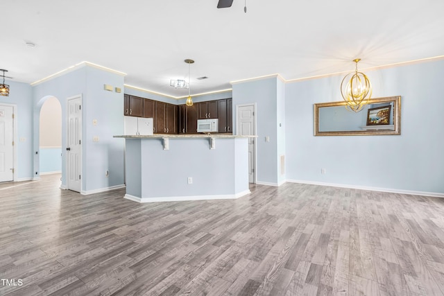 kitchen with white appliances, arched walkways, dark brown cabinets, and decorative light fixtures