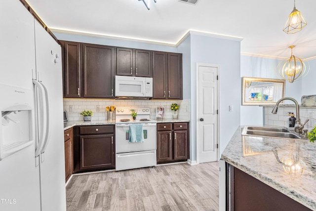 kitchen with light wood-type flooring, white appliances, a sink, and decorative light fixtures