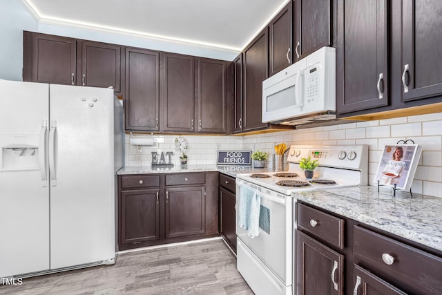 kitchen with light stone counters, white appliances, light wood-style floors, dark brown cabinets, and backsplash