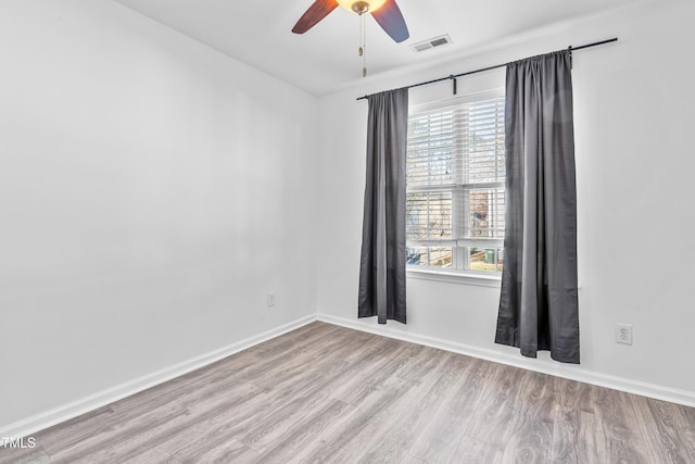 empty room with plenty of natural light, visible vents, light wood-style flooring, and baseboards