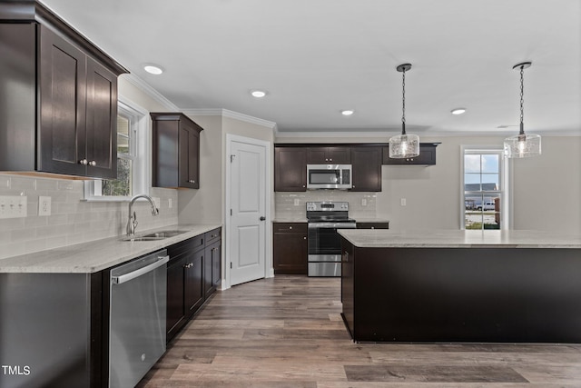 kitchen with sink, wood-type flooring, decorative light fixtures, stainless steel appliances, and light stone countertops