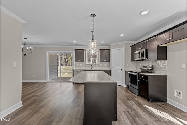 kitchen featuring a center island, light stone counters, stainless steel appliances, crown molding, and dark brown cabinets