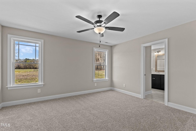 unfurnished bedroom with ceiling fan, ensuite bath, and light carpet