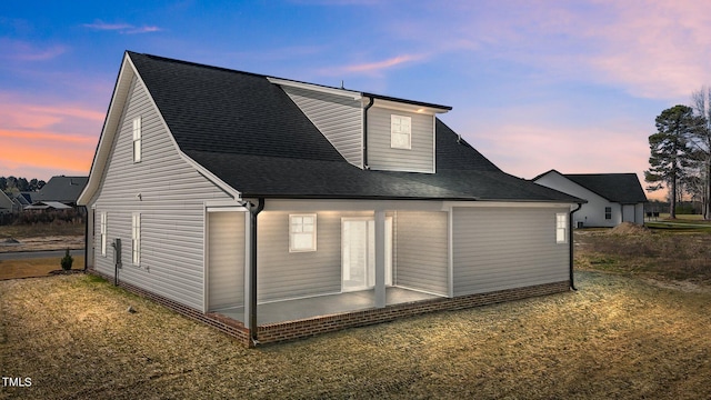 property exterior at dusk with a yard and a patio