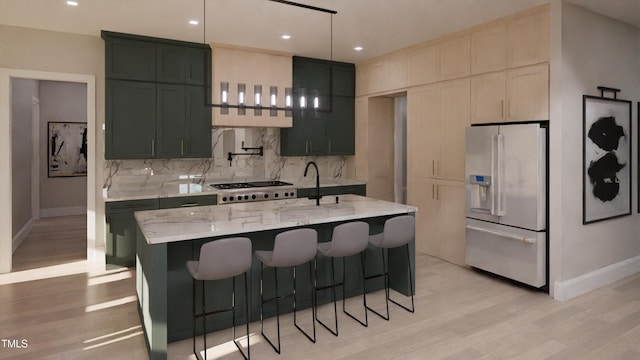 kitchen featuring light hardwood / wood-style flooring, backsplash, fridge with ice dispenser, light stone counters, and an island with sink