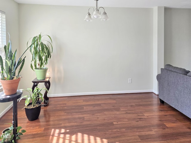 living area with a notable chandelier, baseboards, and wood finished floors