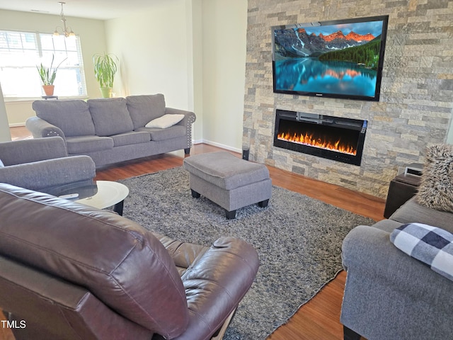 living room with a notable chandelier, a fireplace, baseboards, and wood finished floors